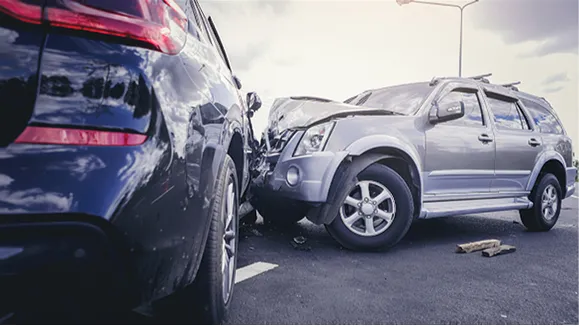 Two SUVs involved in a front-end collision on a paved road under daylight.