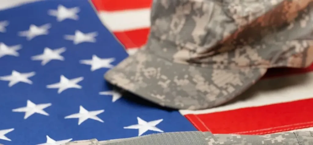Close-up of a U.S. flag with a military camouflage cap placed on top.