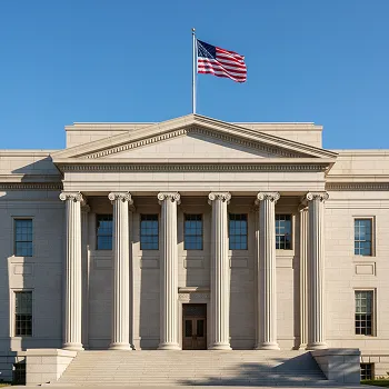 Neoclassical government building with six columns and an American flag against a clear blue sky.